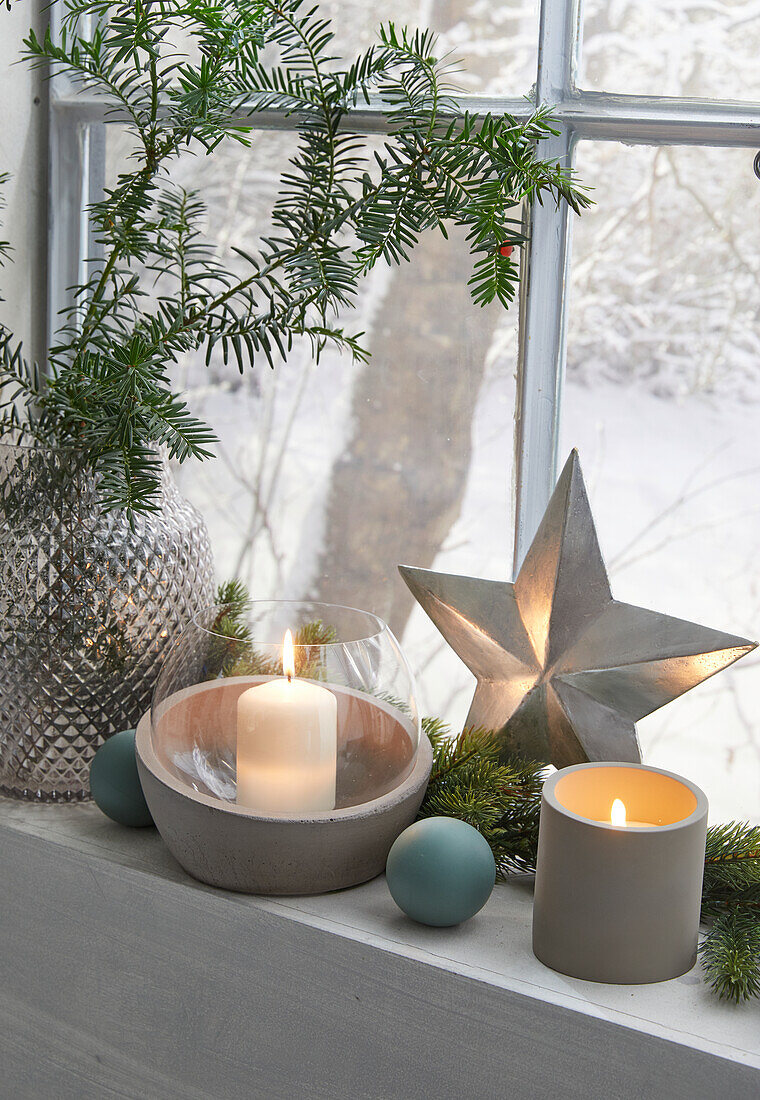 Window sill decorated for Christmas with candles, star and fir branches