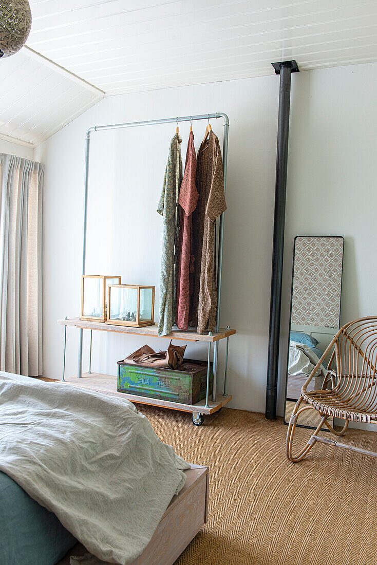 Clothes rack and mirror in bedroom with natural fibre carpet