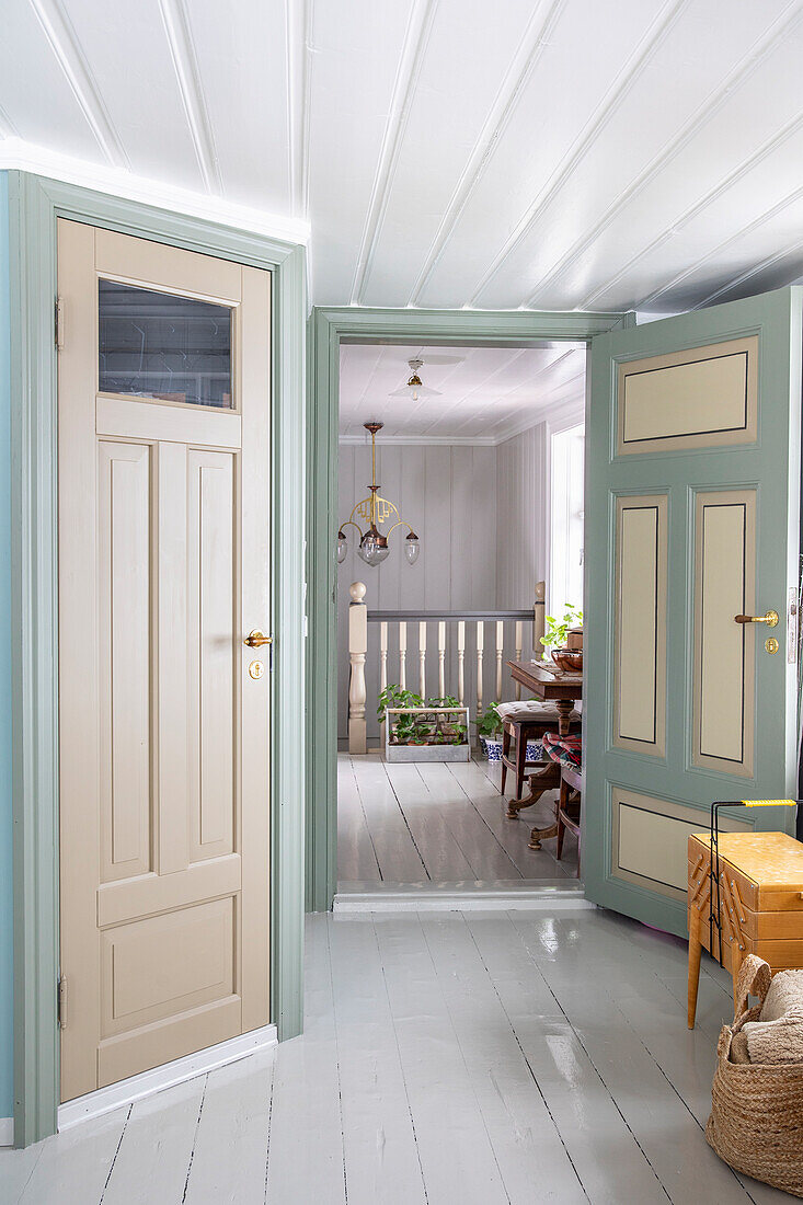 Flur im Landhausstil mit pastellfarbenen Türen und weißem Dielenboden