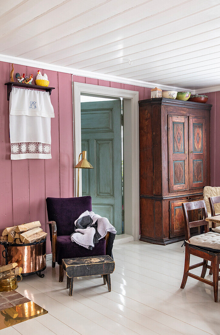 Alter Holzschrank und Polstersessel mit Wolldecke in Zimmer im ländlichen Stil