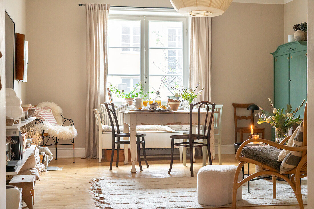 Bright dining room with wooden table, plants on windowsill and vintage furniture