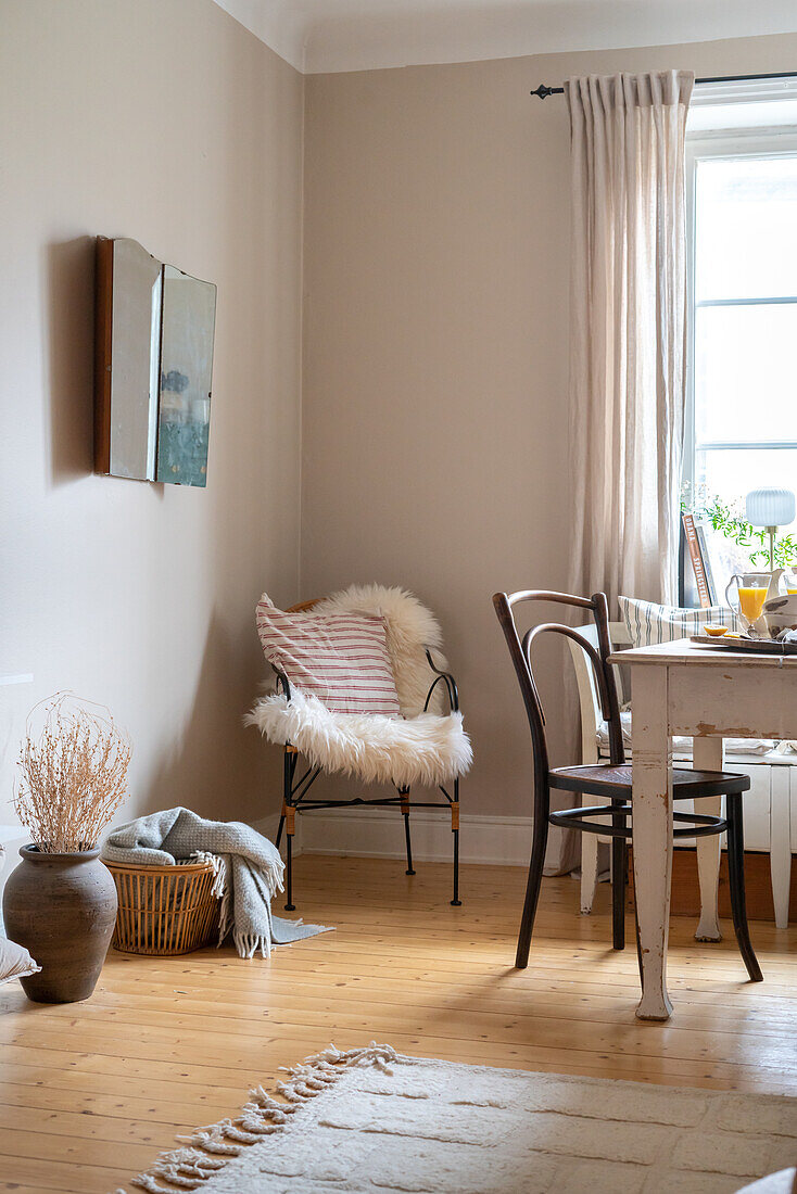Chair with fur and table by the window in a bright room with wooden flooring