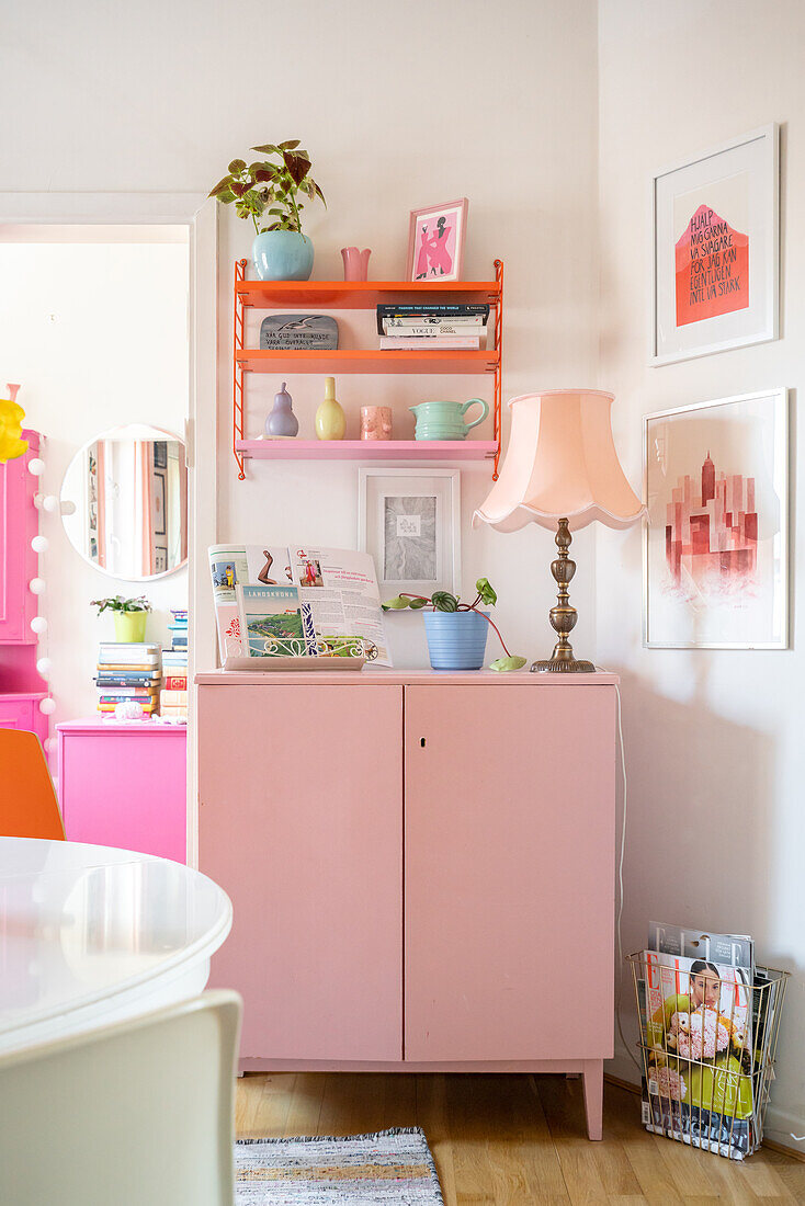 Pink chest of drawers with lamp and decoration in a colourful room