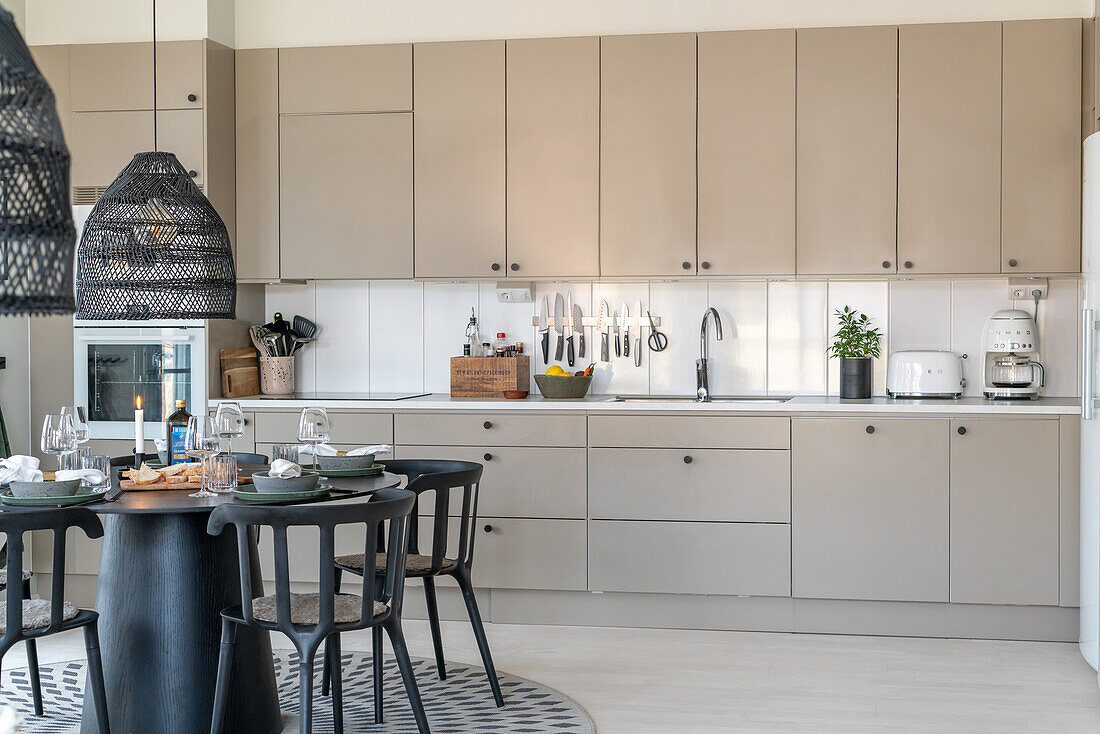 Modern kitchen with light-coloured fronts, dining table and pendant lights