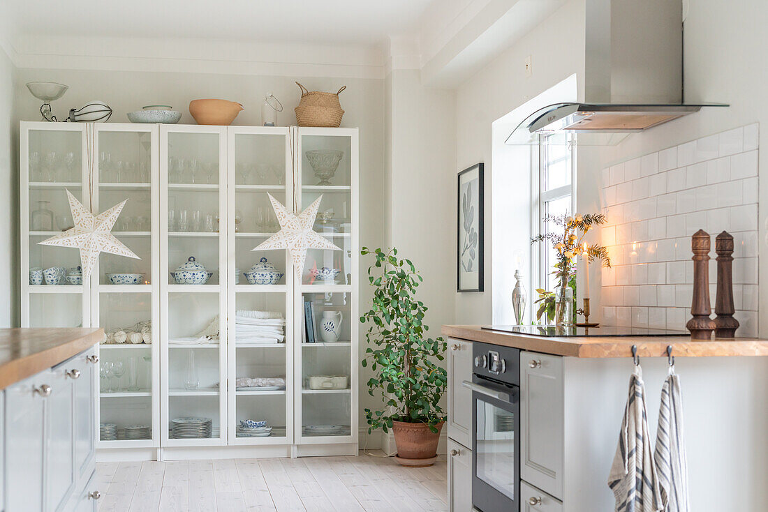 Light-coloured kitchen with white display cabinets and Christmas decorations