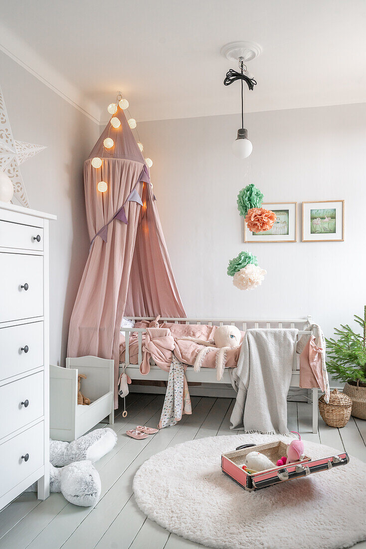 Children's room with canopy, fairy lights and pastel-coloured decorations