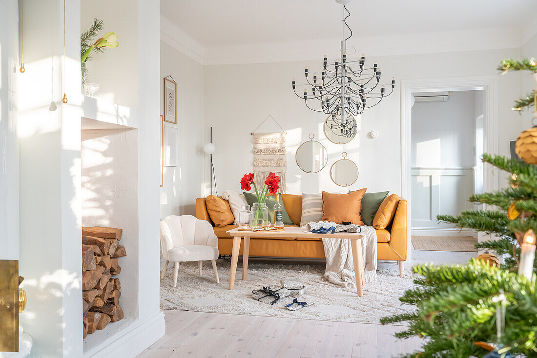 Helles Wohnzimmer mit Kaminholz, Kronleuchter und Weihnachtsdeko