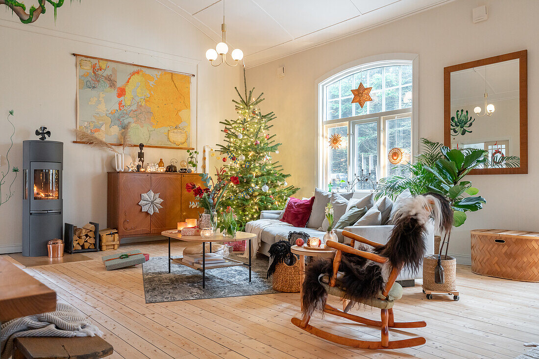 Weihnachtlich geschmücktes Wohnzimmer mit Tannenbaum und Kaminofen