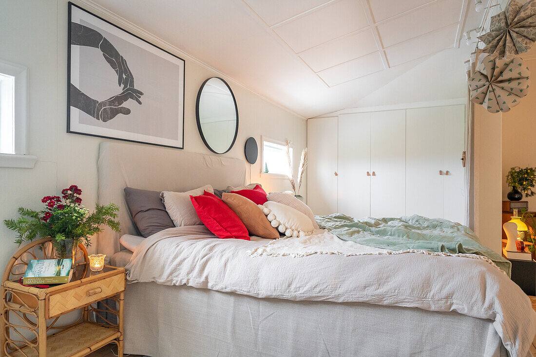 Bedroom with neutral colour scheme, red accent cushions and mural