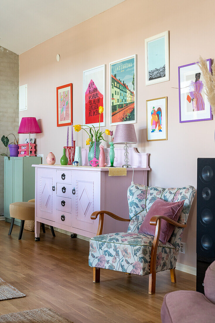 Rosa Sideboard, farblich abgestimmte Bilderrahmen, Sessel mit floralem Muster und Blumen