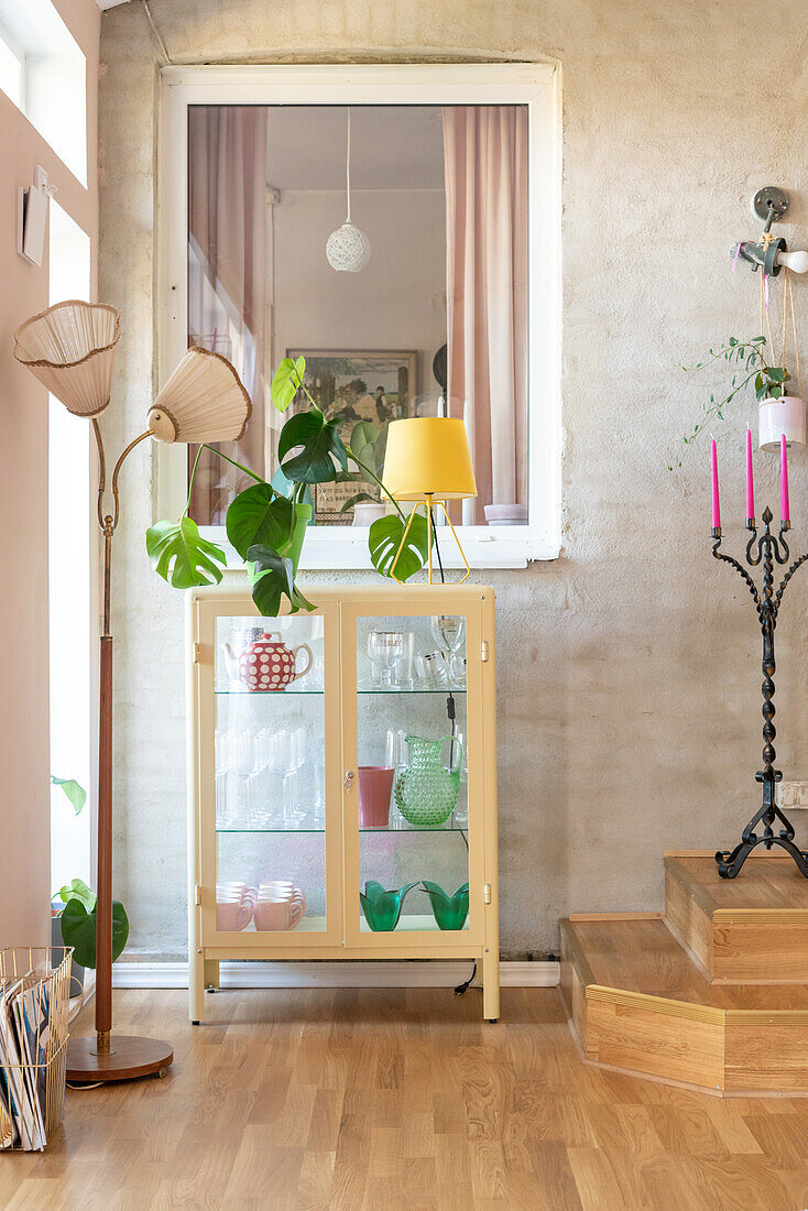 Display cabinet, houseplant, vintage floor lamp and wooden steps