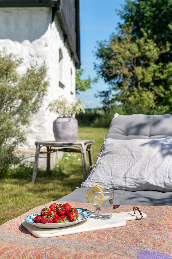 Relaxation corner in the garden with deckchair and a plate of strawberries