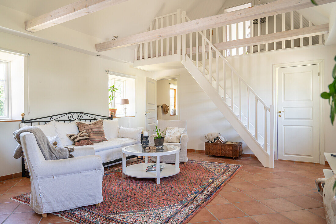 Bright living room with gallery, white couch and oriental carpet