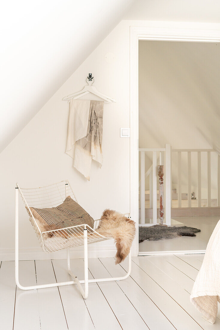 Metal chair with cushions and fur in the bright attic room