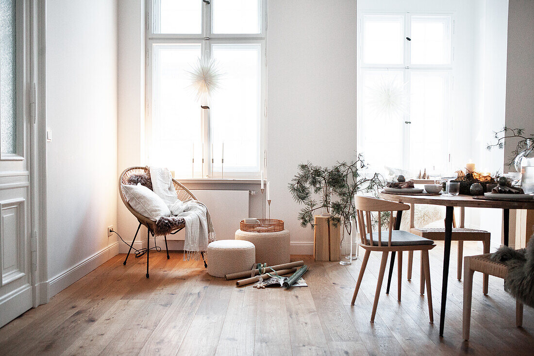 Living room with dining table decorated for Christmas, armchair with fur and pine branches