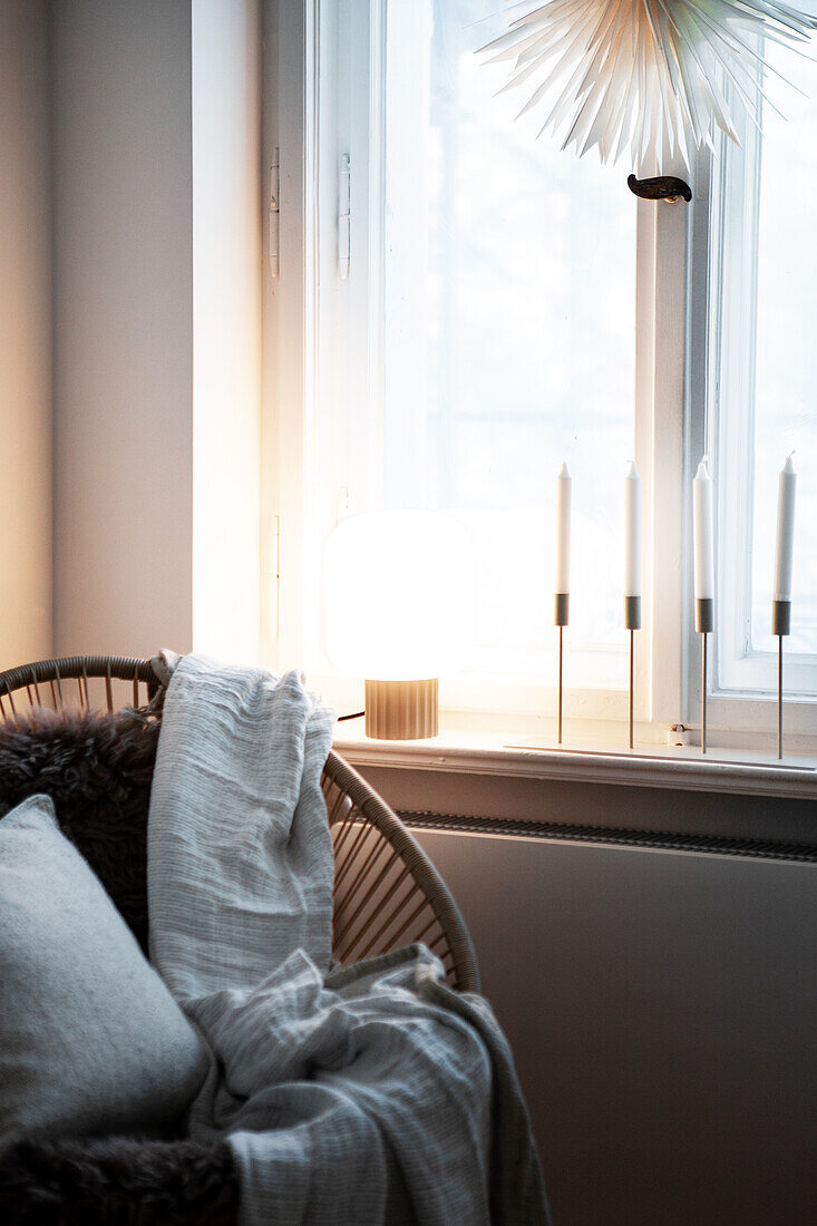 Armchair with fur, blanket and pillow, candles on windowsill