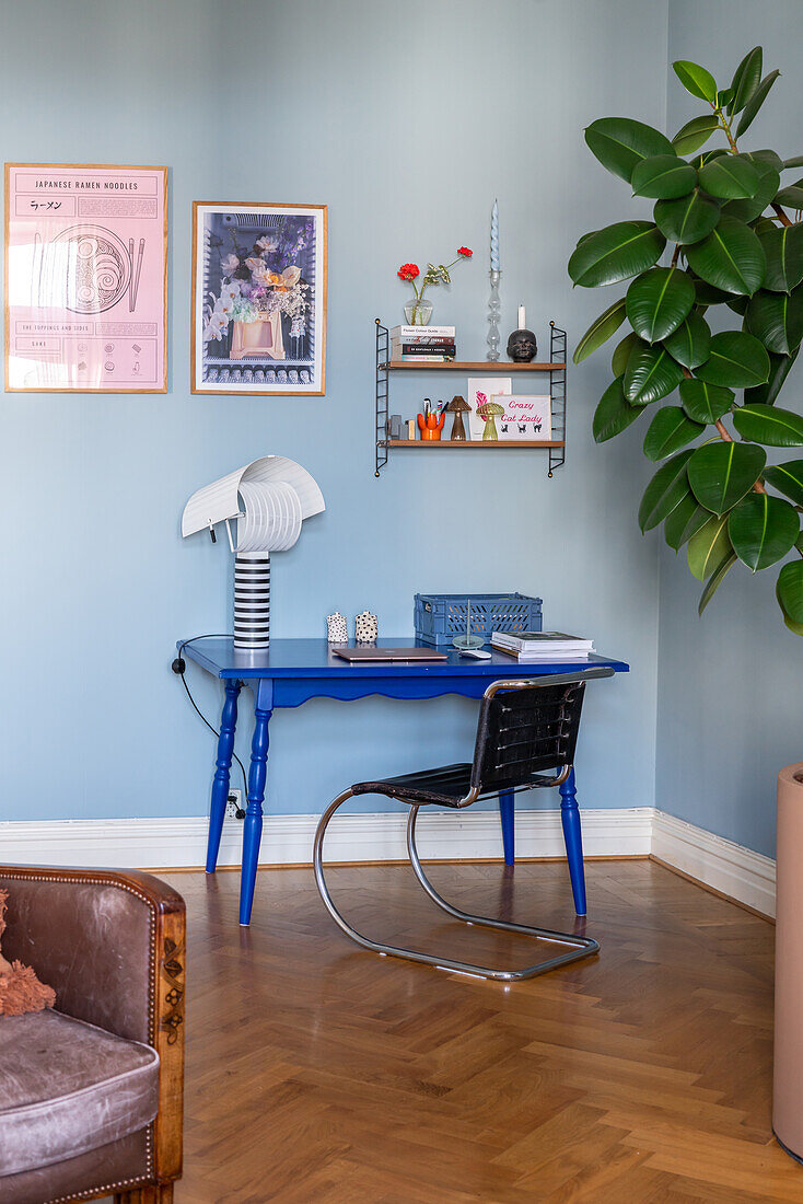 Work corner with blue desk and decorative shelf on blue wall