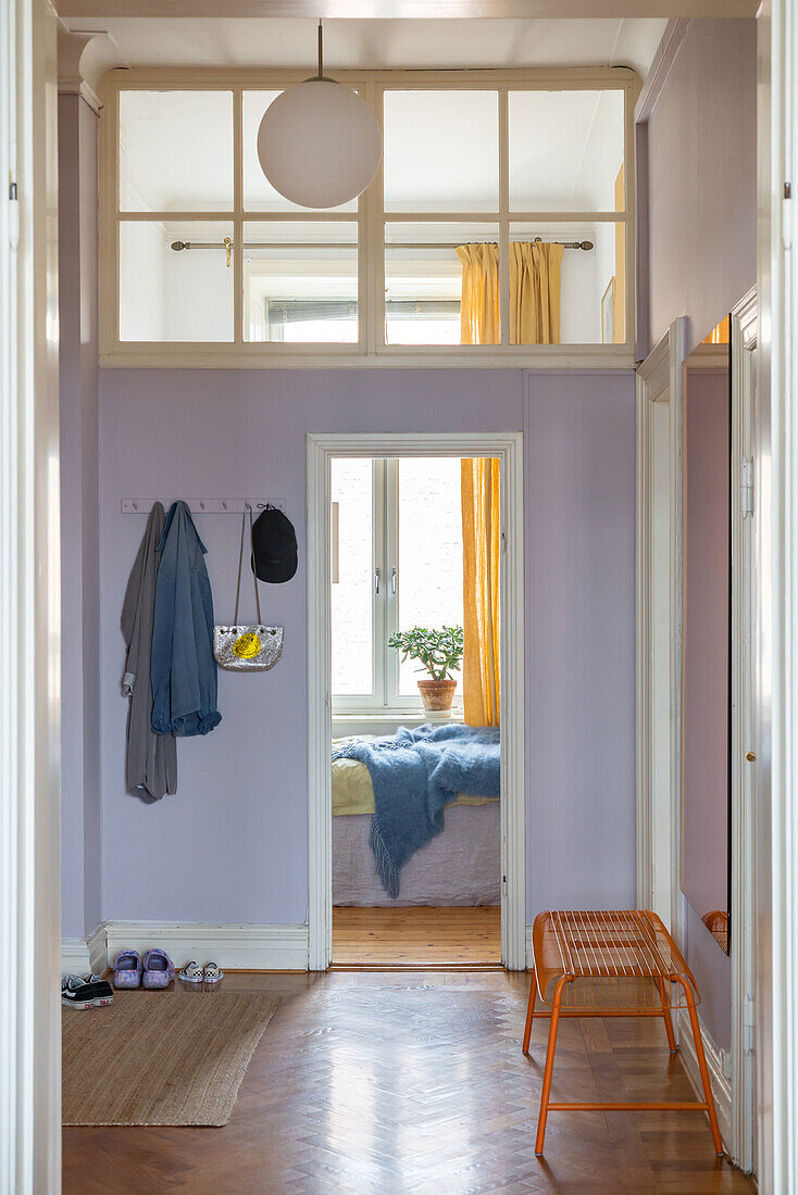 Hallway with purple walls, coat hooks and a view of the bedroom