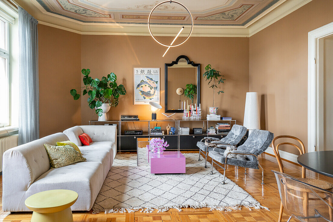 Living room with seating, ceiling decoration, plants and geometric hanging lamp