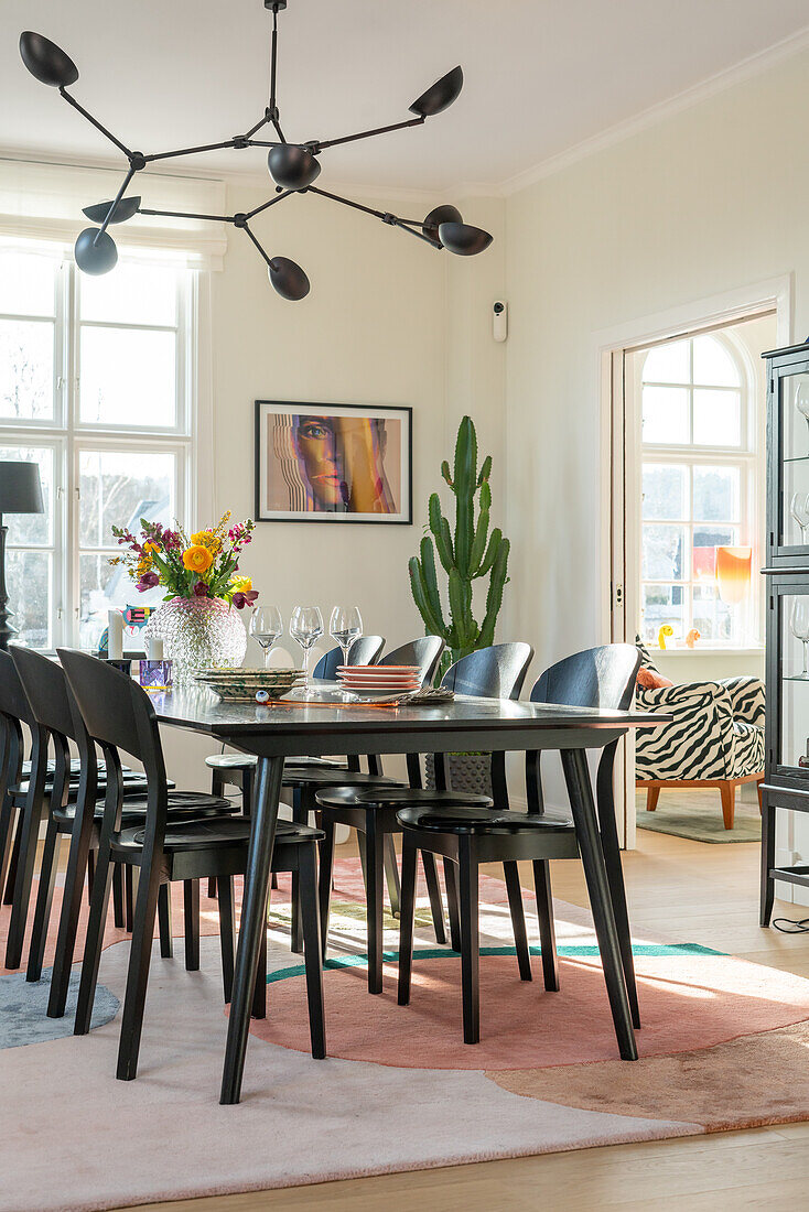 Dining table with black chairs and colorful bouquet of flowers in a bright room