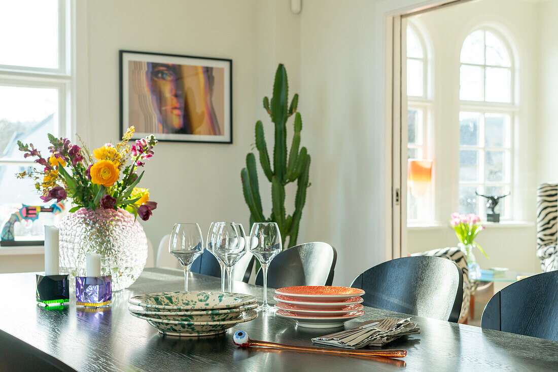 Esstisch mit buntem Blumenarrangement und Kaktus im Hintergrund