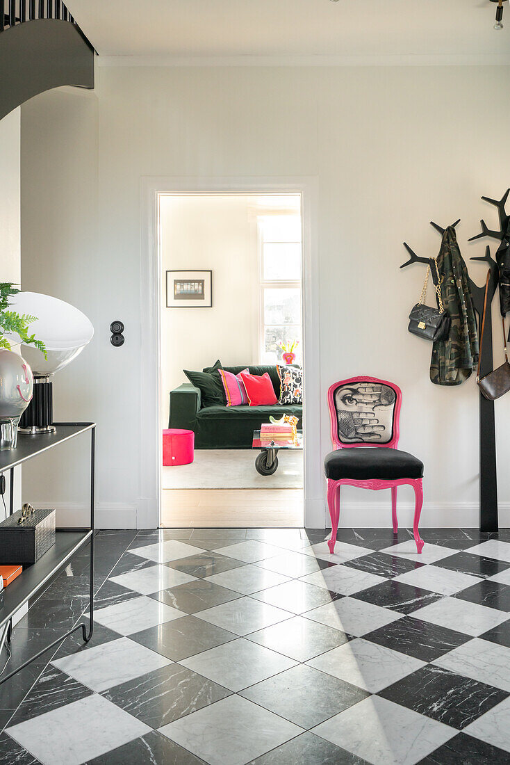 View through a doorway into a living room, black and white floor and pink and black chair with motif