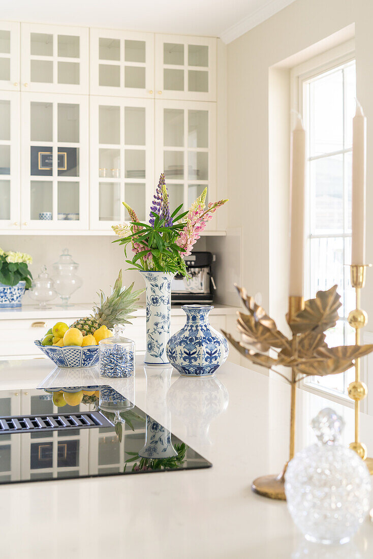 Light-colored kitchen with floral arrangement and fruit bowl