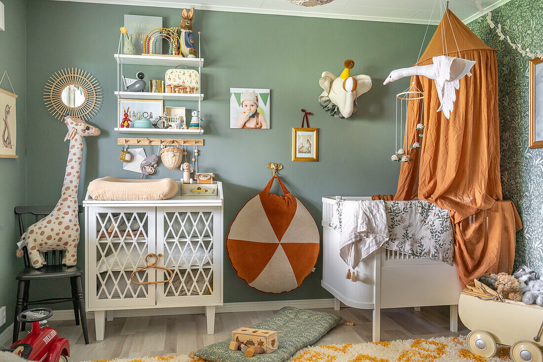 Crib with canopy, varied decoration and green walls in children's room