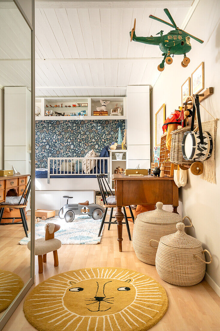 Children's room with bed, patterned wallpaper, lion rug and toys