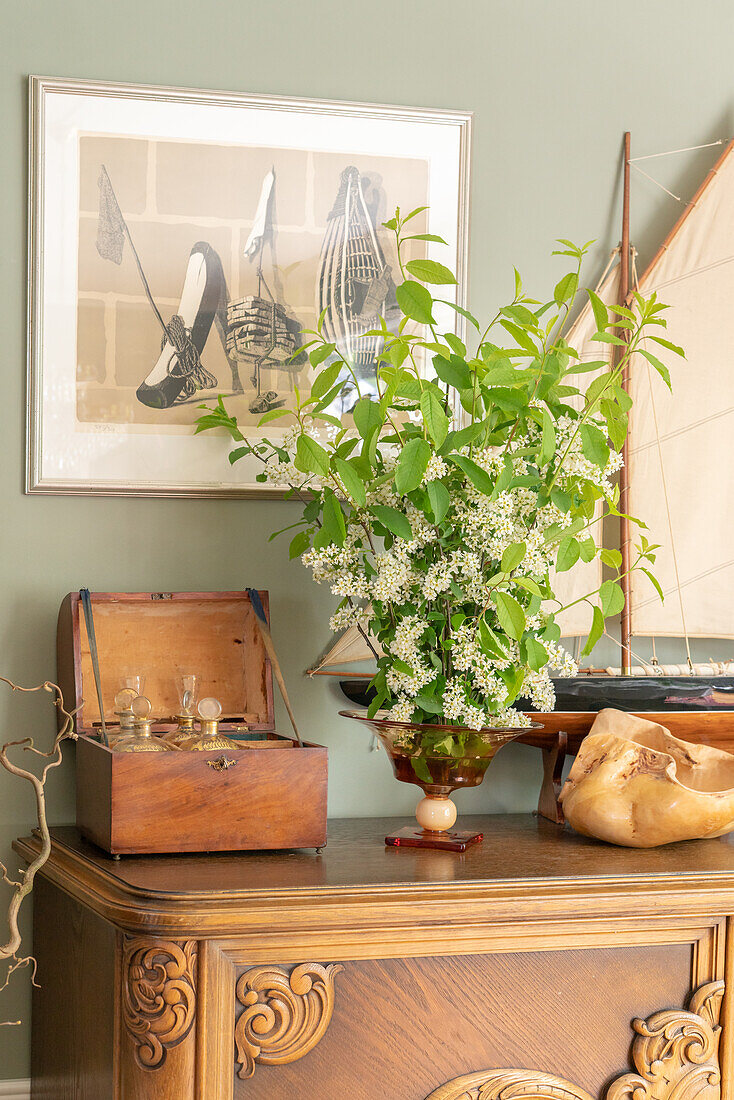 Plant arrangement on antique wooden chest of drawers with maritime decorations