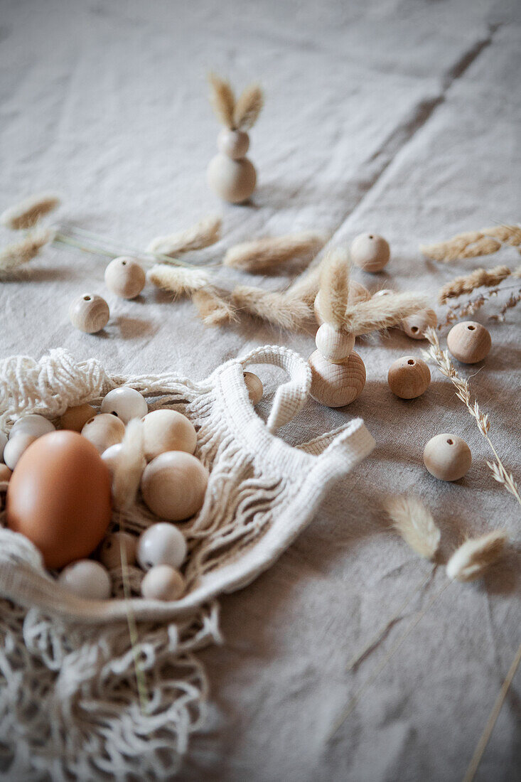 Wooden baubles and eggs on linen cloth with dried flowers