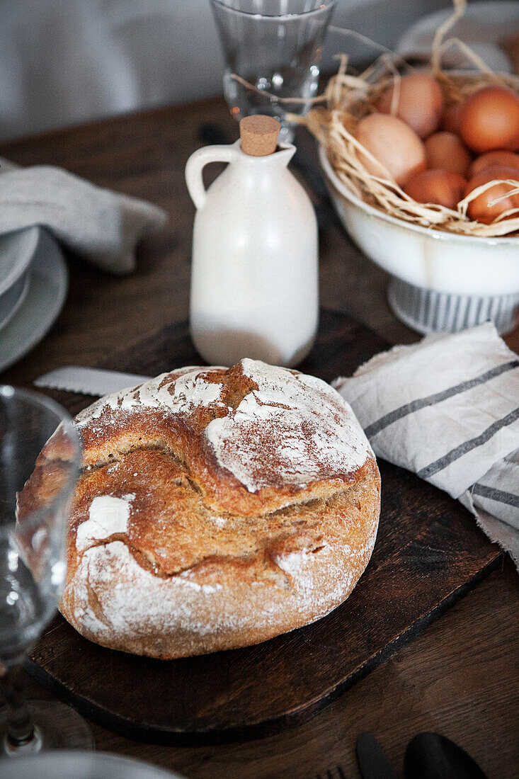 Rustic bread on a wooden table with eggs and milk bottle