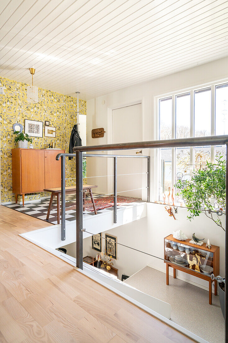 Hallway with vintage wallpaper, banister and black and white chequered floor