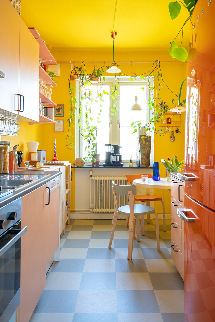Orange-colored fridge and pink cupboards in kitchen with yellow walls
