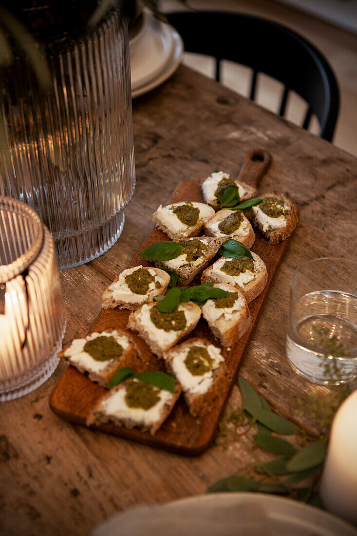 Canapés with cream cheese and pesto served on wooden board