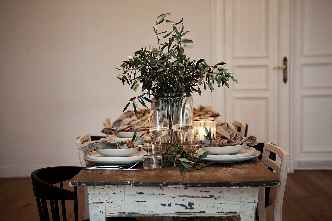 Table setting with olive branches in a vase