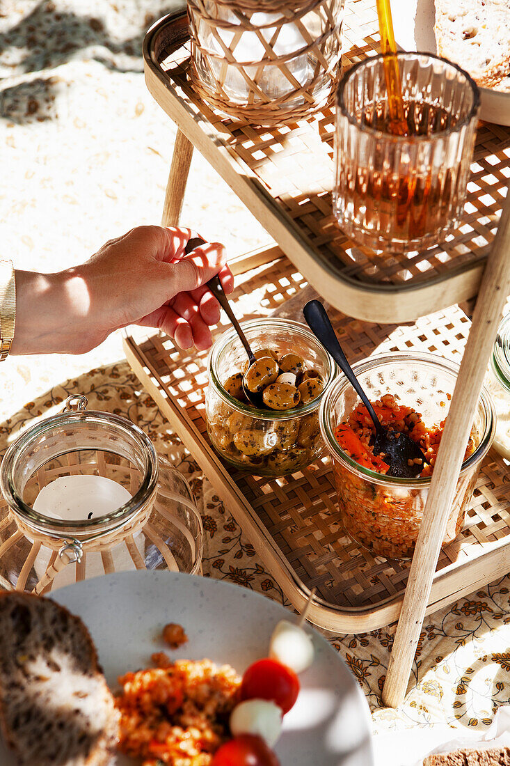 Picknicktisch mit Oliven und Humus in Einmachgläsern