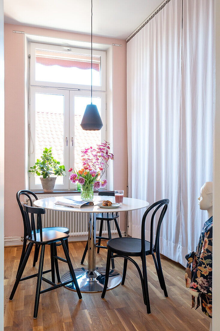 Dining area with round table, black chairs and tulips