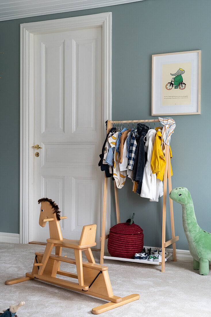 Children's room with wooden rocking horse, clothes rack and picture