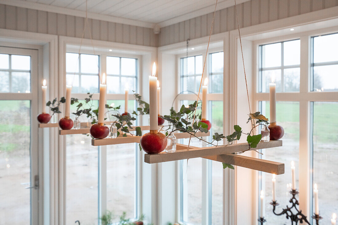 Hanging wooden candle holder decorated with apples, candles and greenery