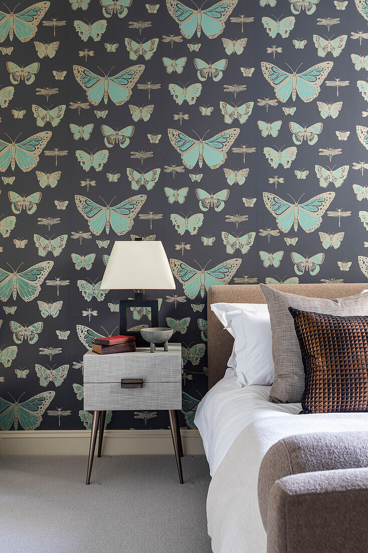 Double bed and mid-century bedside table in the guest room, wallpaper with butterfly motif