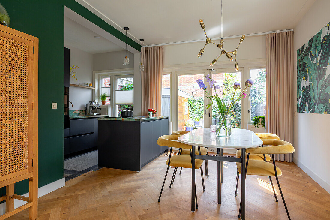 Open-plan living room with kitchen, dining table and green wall design