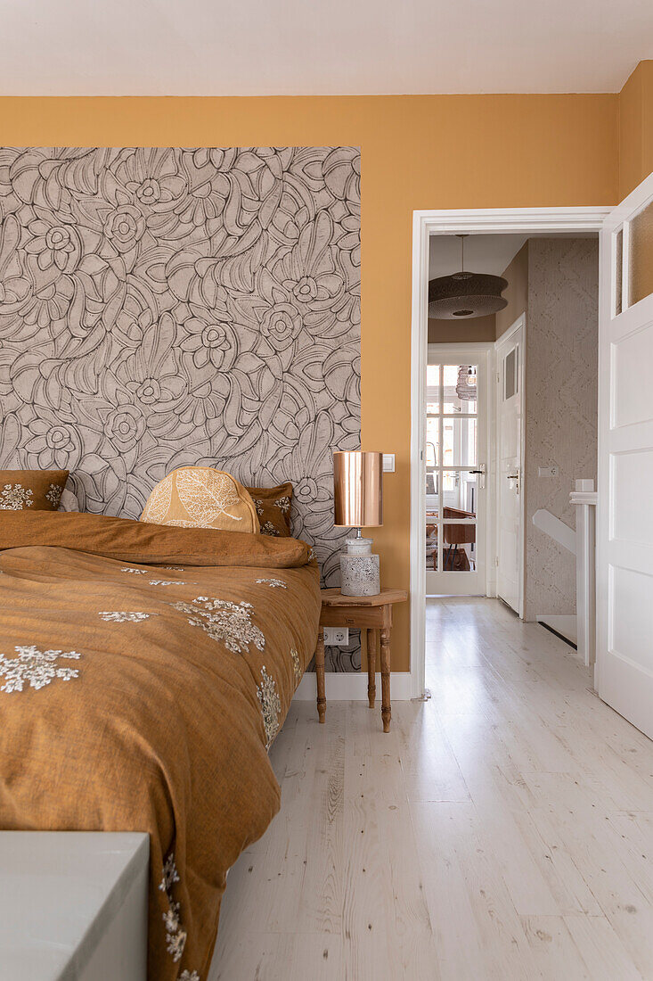 Bedroom with patterned wallpaper and ochre-coloured walls