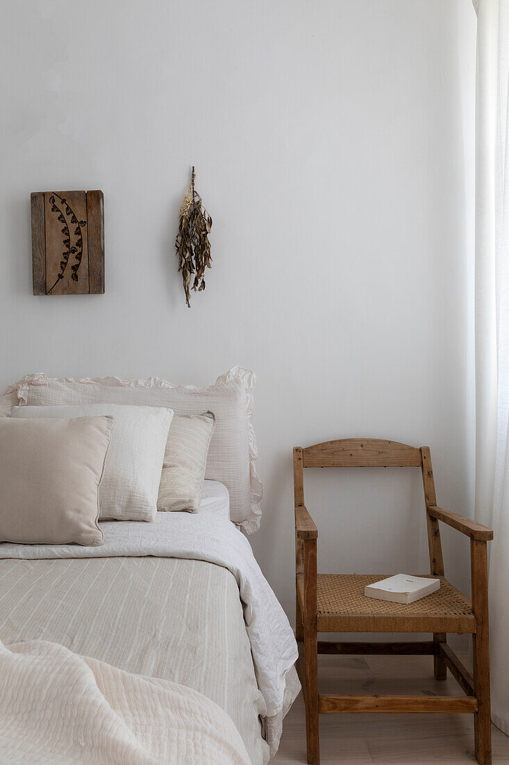 Schlafzimmer in Naturtönen mit Holzstuhl und heller Bettwäsche