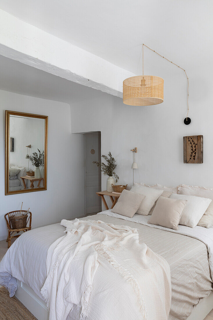 Light-coloured bedroom with rattan lamp