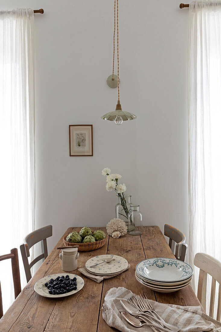 Holztisch mit rustikalem Geschirr und Blumendekoration in neutralem Esszimmer