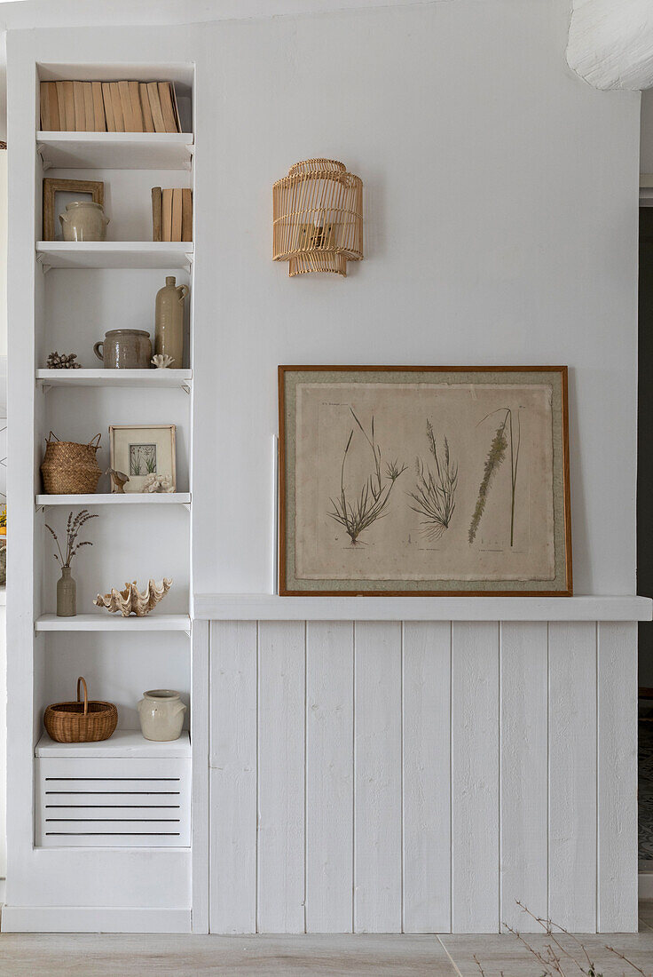 Shelf with decoration and picture of grasses above white wall panelling