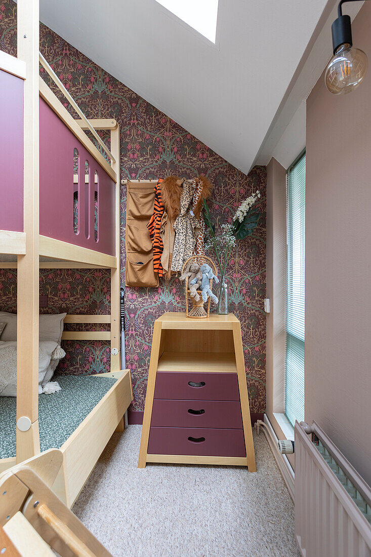 Children's room with bunk bed and floral wallpaper under a sloping roof