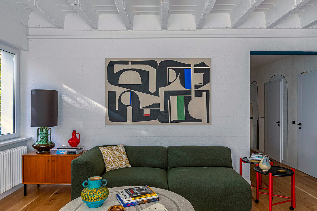 Green sofa, mid-century cabinet with table lamp and modern art on the wall in a living room