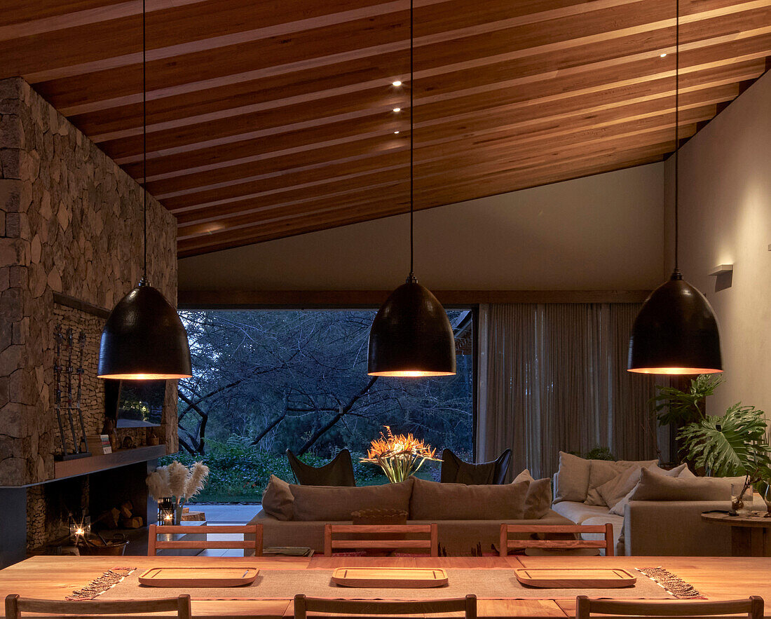 Dining area, hanging lights above in open living room at dusk